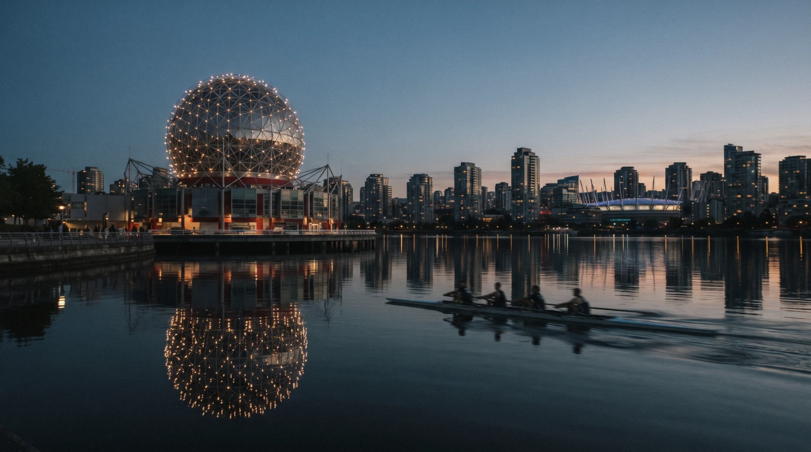 The geodesic dome of Science World lit at dusk and reflected in False Creek in Vancouver