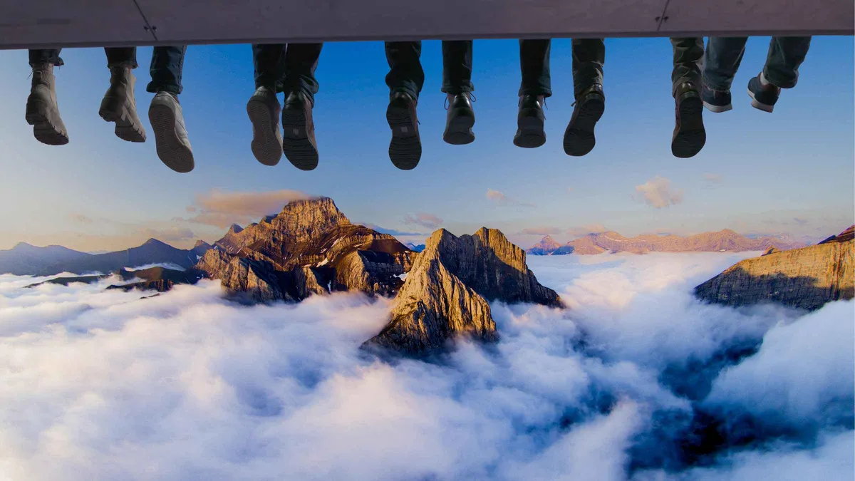 Riders with feet dangling before the spherical screen of the flying theatre at Canada Place, FlyOver Canada experience Vancouver